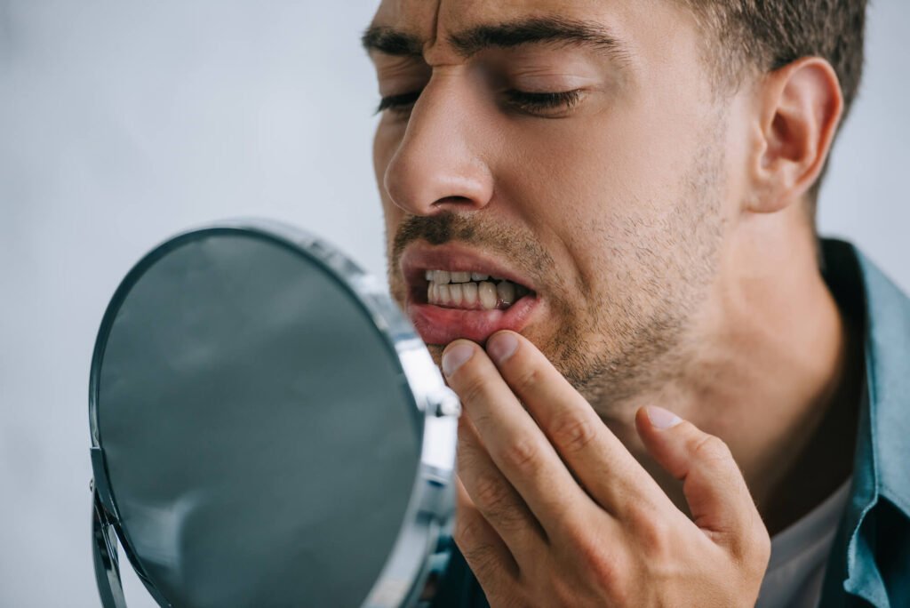 man checking his teeth in the mirror before going to a dentist in Cameron Park