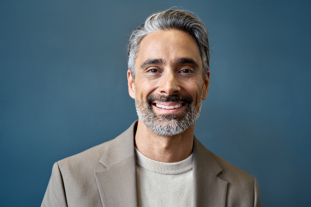 A distinguished, smiling man with grey hair and beard, showcasing his perfect smile for Dental Implants at Forest Ridge Dental Health & Wellness