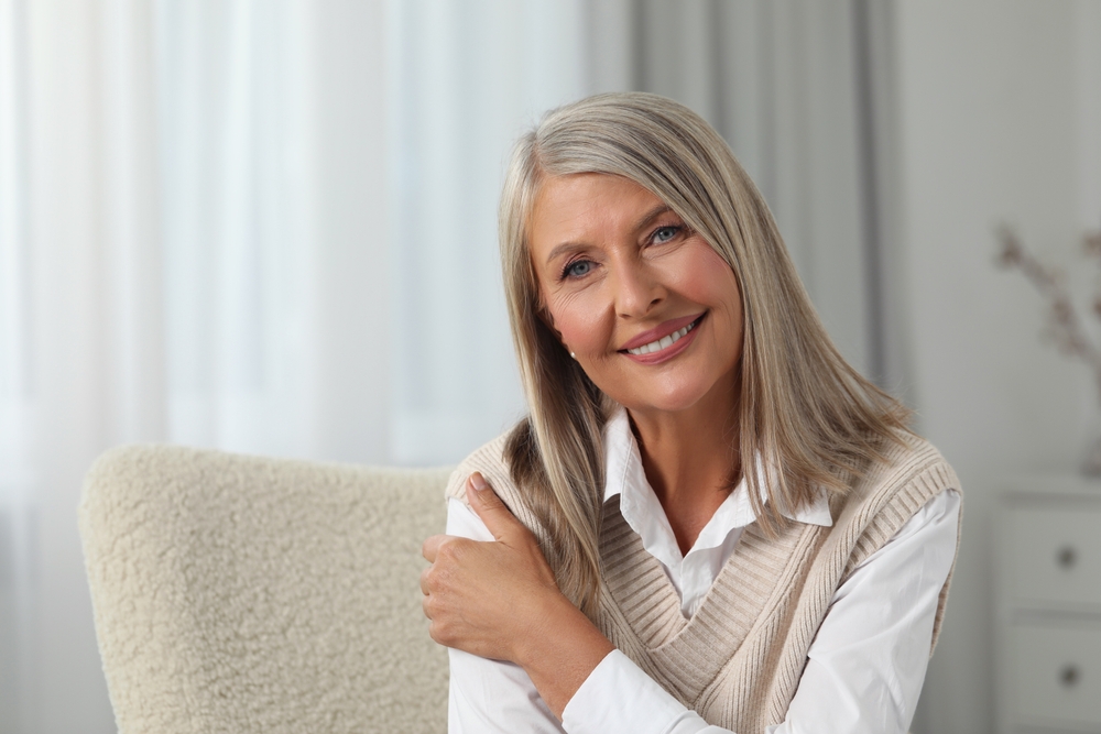 A beautiful mature woman with gray hair smiling confidently, advertising Dentures at Forest Ridge Dental Health & Wellness